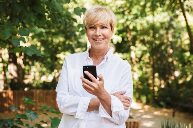 Mujer madura feliz que usa el teléfono móvil