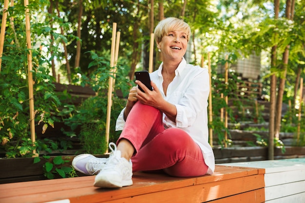 Mujer madura feliz que usa el teléfono móvil