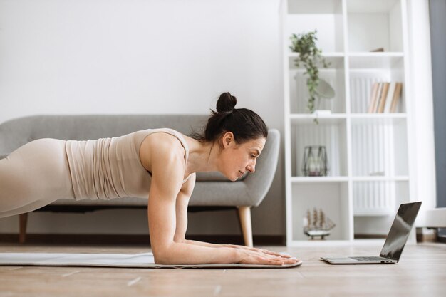 Mujer madura fortaleciendo todo el cuerpo con postura de tabla durante el entrenamiento de yoga