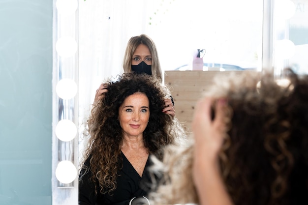 Mujer madura frente a un espejo en una peluquería junto a un trabajador