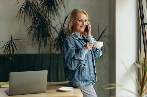 Mujer madura hablar teléfono una bebida café