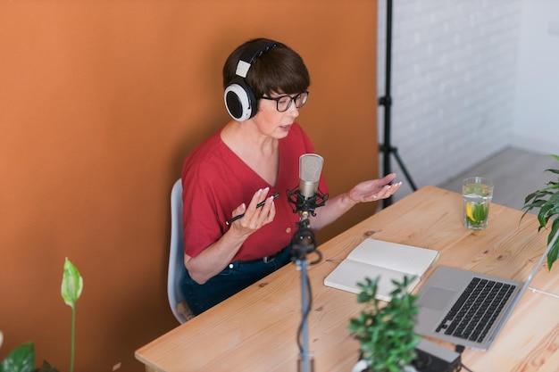 Mujer madura haciendo grabación de podcast para su programa en línea atractiva mujer de negocios usando auriculares