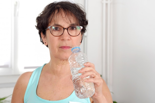 Mujer madura hermosa fitness con botella de agua