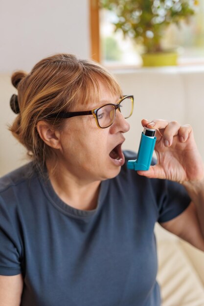 Mujer madura con inhalador con ataque de asma en casa