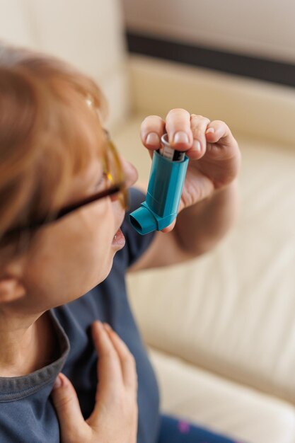 Mujer madura con inhalador con ataque de asma en casa