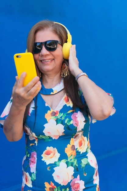 Mujer madura latina con smartphone y auriculares en la ciudad.