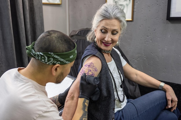 Mujer madura de moda en el salón de tatuajes