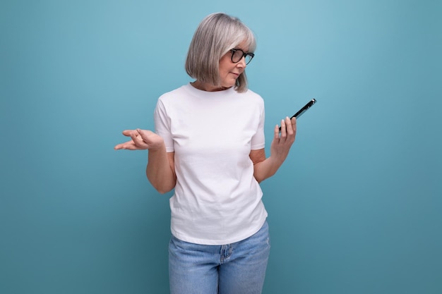 Mujer madura de pelo gris que estudia el teléfono inteligente de tecnología digital en un fondo de estudio brillante