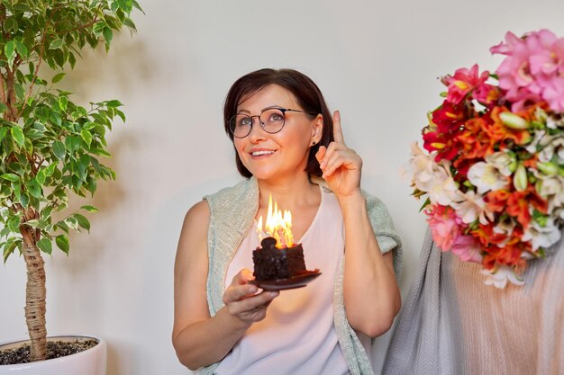 Mujer madura con un pequeño pastel de cumpleaños con velas encendidas