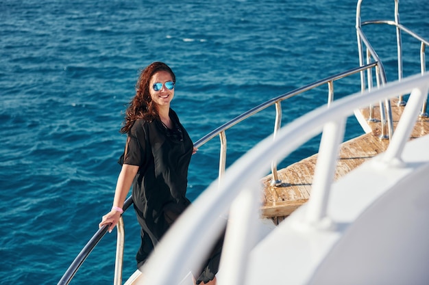 Mujer madura de pie en el yate y disfrutando de sus vacaciones en el mar