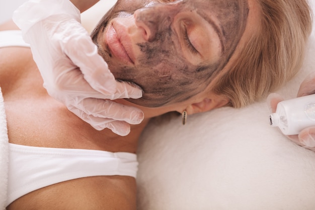 Mujer madura recibiendo tratamiento facial en el salón de belleza