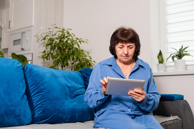 Mujer madura relajada sosteniendo una tableta usando una aplicación de atención médica