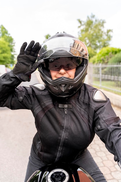 Foto mujer madura con ropa de motociclista montando una motocicleta moderna al aire libre