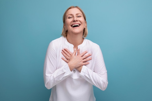 Mujer madura rubia en una blusa blanca con un buen corazón está lista para abrazos