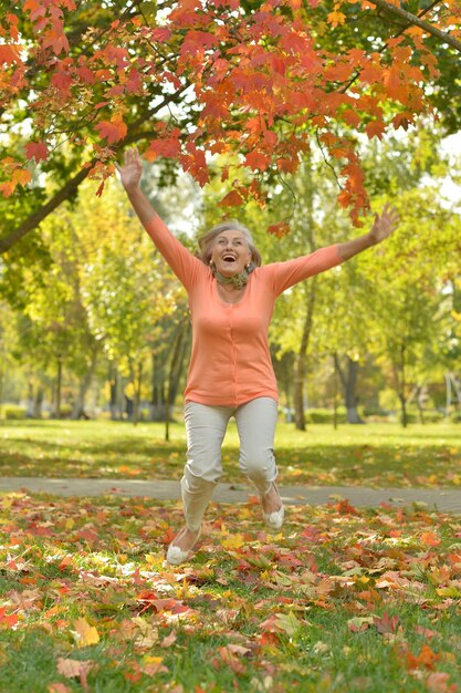 Mujer madura saltando al aire libre en otoño