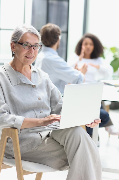 mujer madura, sentado, con, computador portatil, mirar cámara del juez