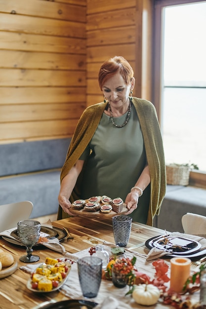 Mujer madura sirviendo la cena en la mesa