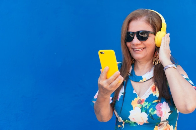 Mujer madura con smartphone y auriculares en la ciudad.