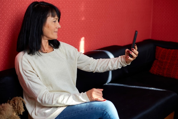 Mujer madura sonriente feliz sosteniendo teléfono inteligente con videollamada