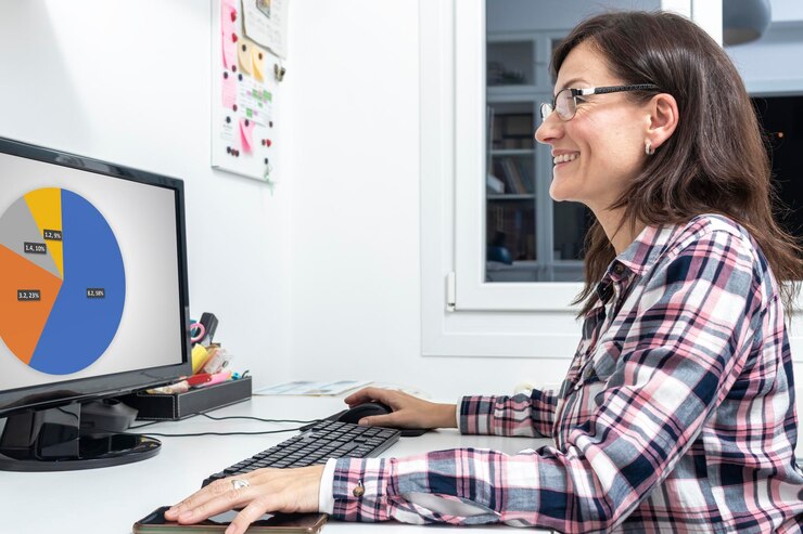 Foto una mujer madura sonriente con gafas mirando una pantalla de computadora con un gráfico de pastel