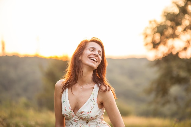 Foto mujer madura sonriente de pie contra el cielo durante la puesta de sol