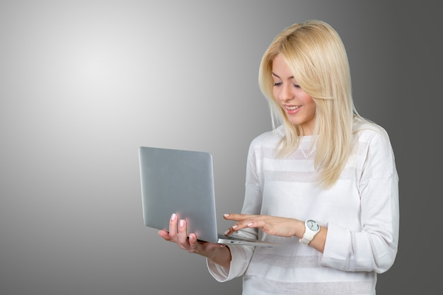 Mujer madura sonriente que sostiene el ordenador portátil