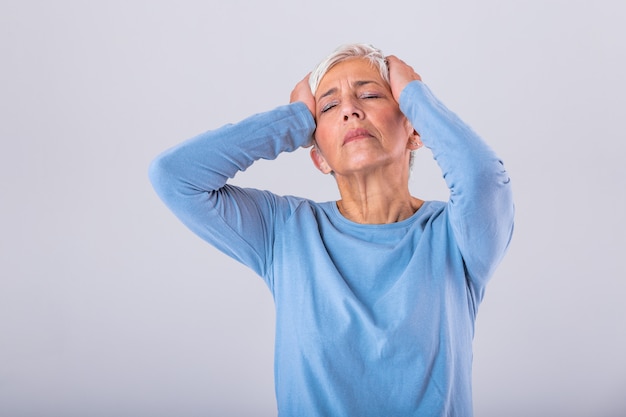 Mujer madura sosteniendo su cabeza con las manos mientras tiene dolor de cabeza