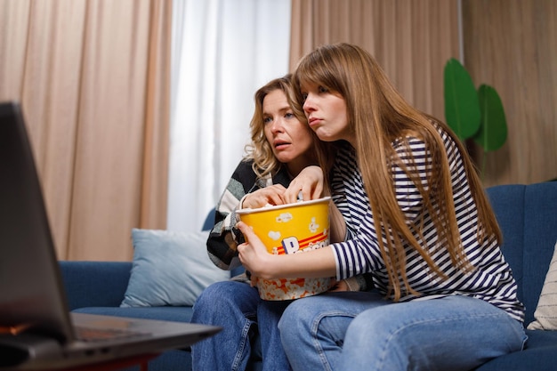 Mujer madura y su hija adulta viendo una película de terror en una laptop