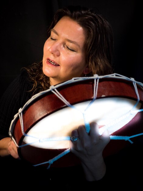 Foto mujer madura tocando música contra un fondo negro