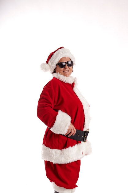 Mujer madura vestida como Santa Claus con gafas de sol sobre un fondo blanco.