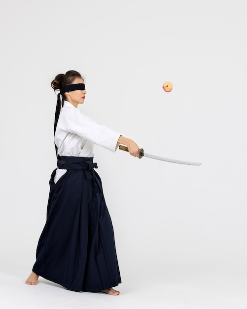 Mujer maestra de aikido en kimono samurai hakama tradicional con cinturón negro con espada katana en blanco