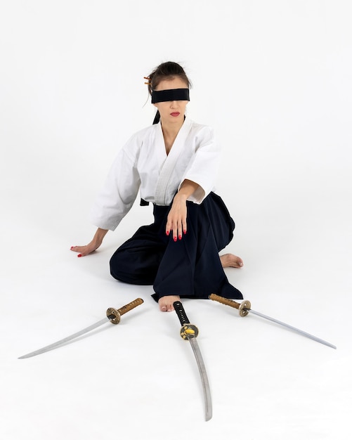 Foto mujer maestra de aikido en kimono samurai hakama tradicional con cinturón negro con espada katana sobre fondo blanco estilo de vida saludable y concepto deportivo