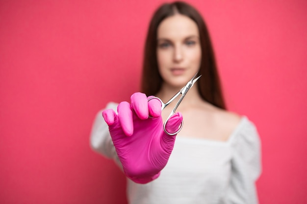 mujer maestra de manicura o esteticista de cuidado de uñas sosteniendo unas tijeras de manicura. Tijeras para cutículas.