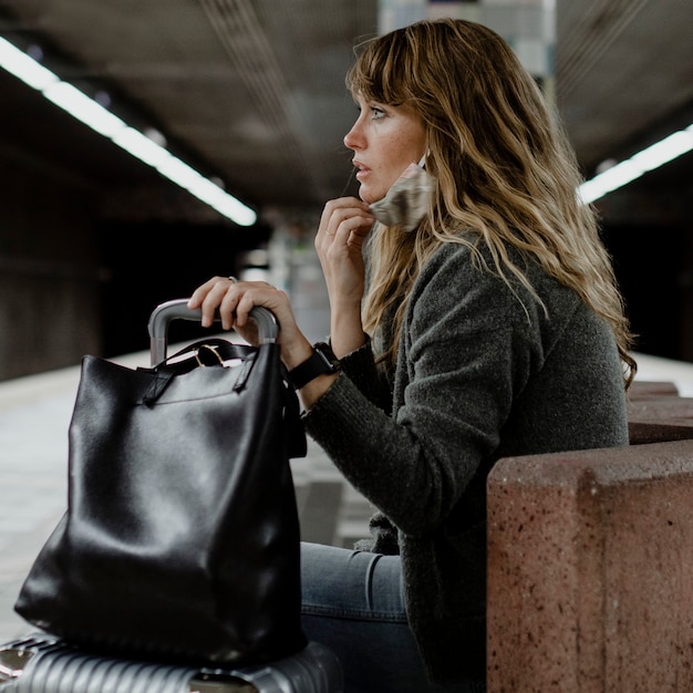 Mujer con maleta esperando el tren durante la pandemia de coronavirus