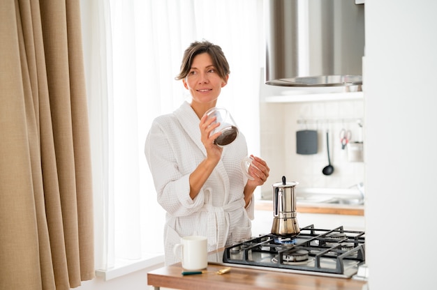 mujer en la mañana prepara café en la cocina