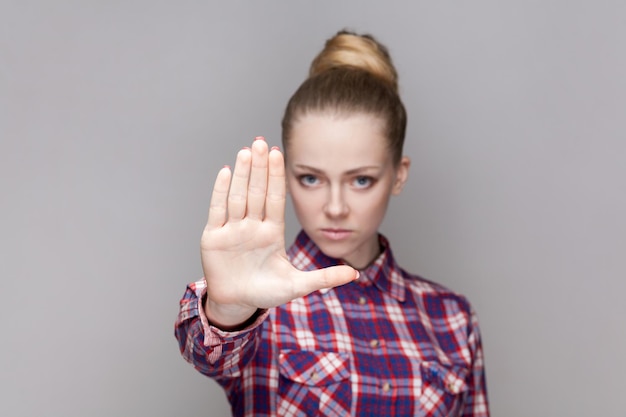 Foto mujer mandona seria con peinado de pan que muestra el gesto de prohibición muestra el signo de la palma de la mano