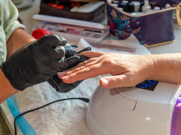 Mujer de manicura aplicando aceite de cuticle después de quitar el esmalte viejo para la pintura permanente de uñas