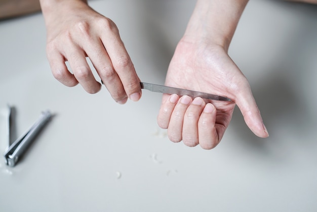 La mujer manicura los archivos de las uñas