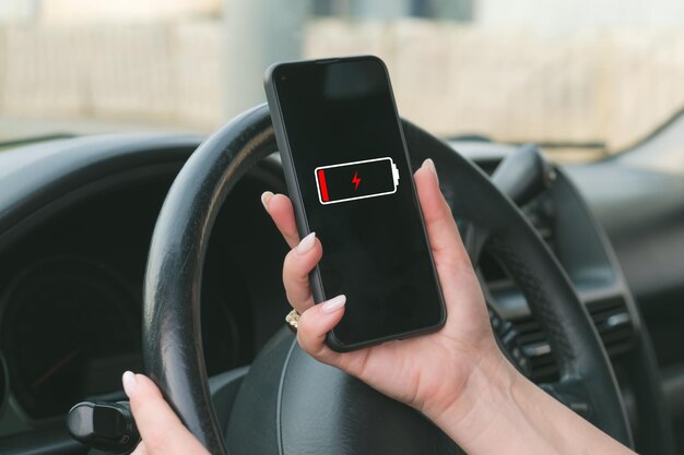 Mujer con manicura sostiene un teléfono inteligente frente al volante de un automóvil