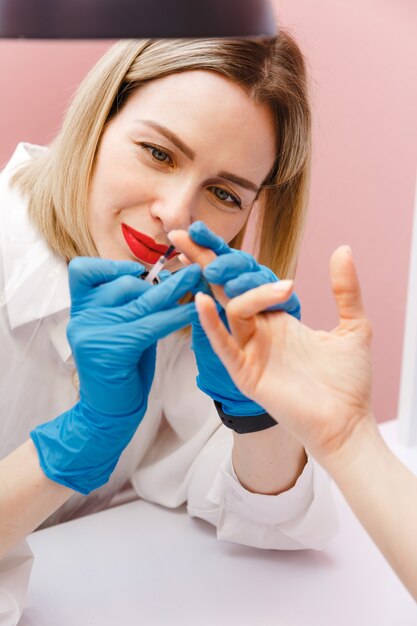 Foto mujer manicurista cubre las uñas con esmalte de uñas para el cliente en salón de belleza