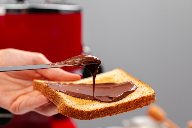 Mujer mano cocinar tostadas con pasta de chocolate