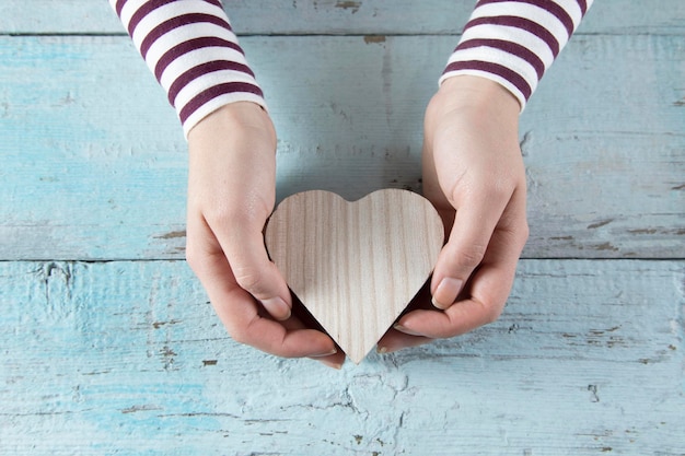 Mujer mano corazón de madera en la mesa