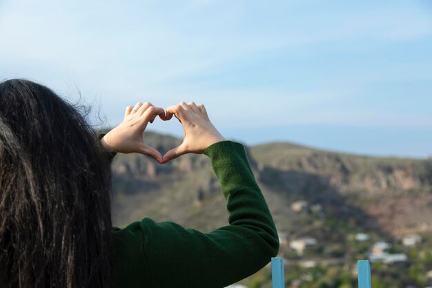 Mujer mano corazón en la naturaleza