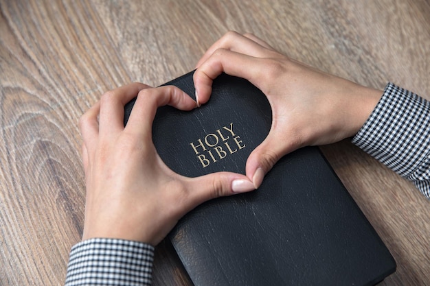 Foto mujer mano corazón en la santa biblia