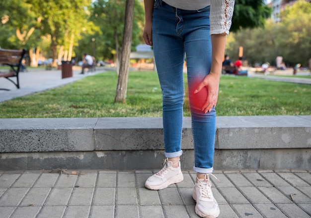 Mujer mano en dolor de rodilla en streetxA