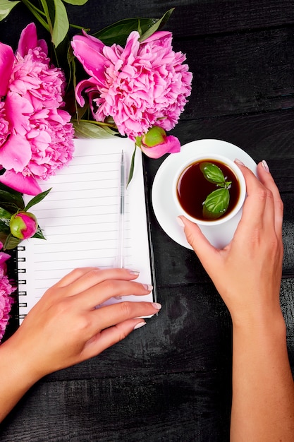 Mujer mano escribiendo diario, o carta, nota con taza de café.
