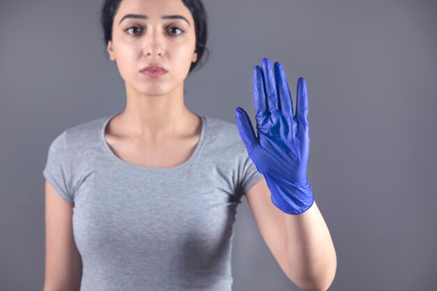 Foto mujer mano guante azul y señal de stop