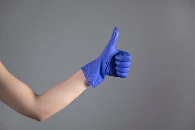 Foto mujer mano guante azul y signo bien