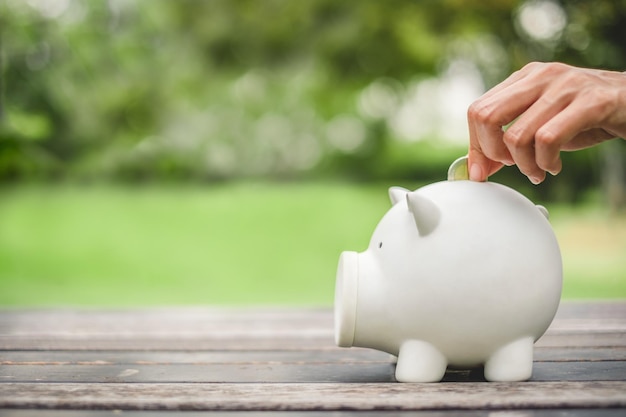 Mujer mano poniendo moneda en cerdito para ahorrar dinero riqueza y concepto financiero