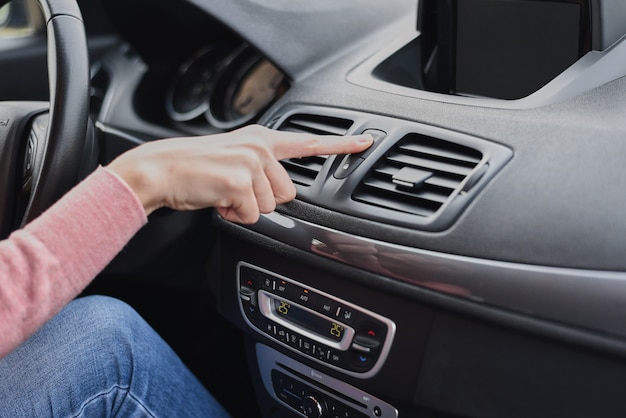 Mujer mano presione el botón de parada de emergencia en el automóvil